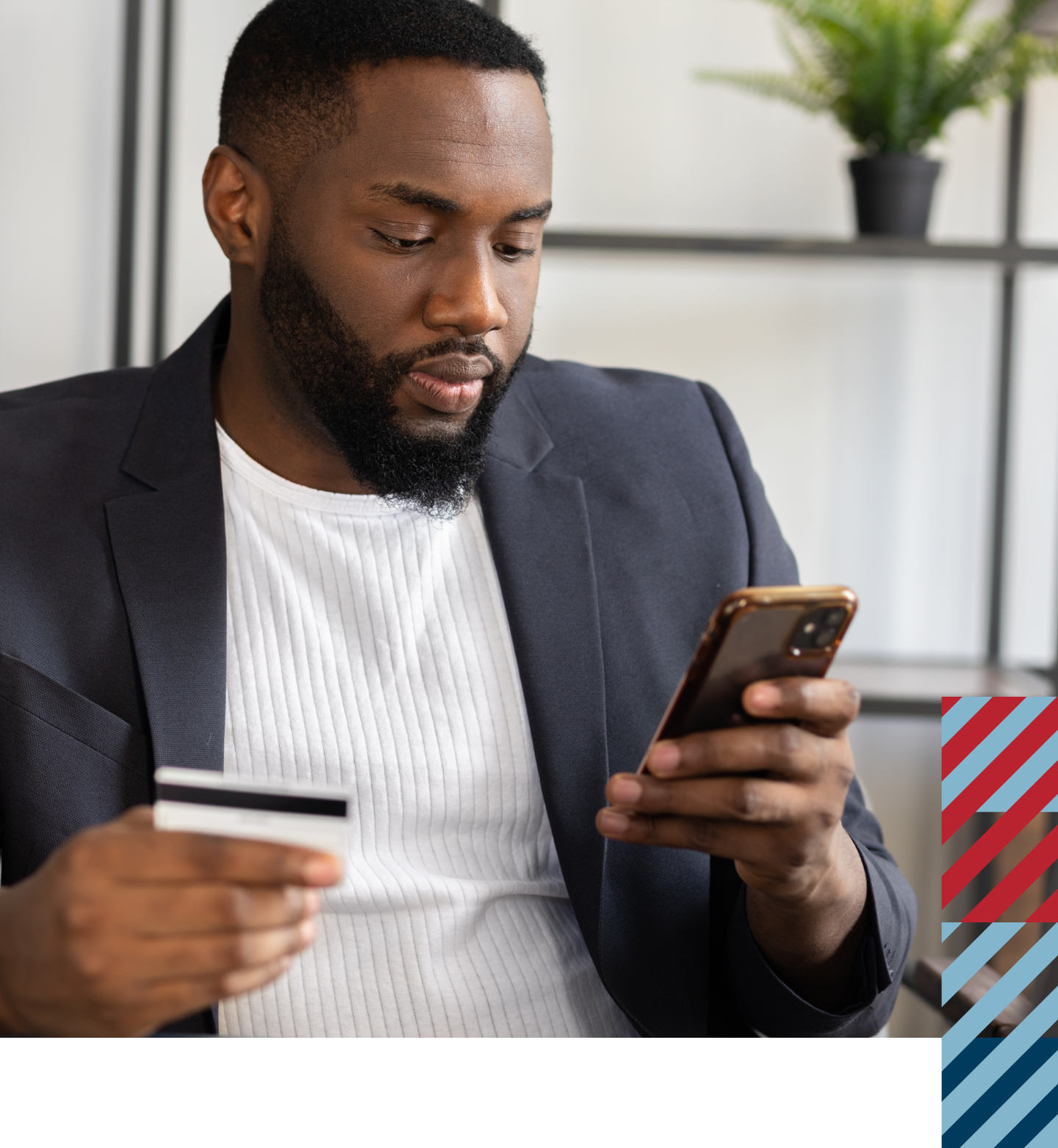 A man looking at his phone while holdinng a credit card.